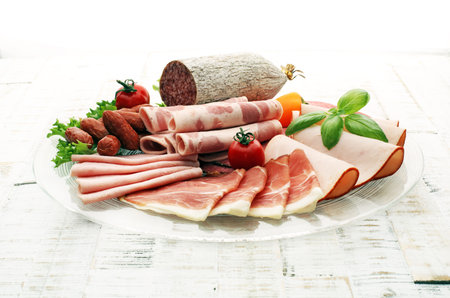 Food tray with delicious salami, pieces of sliced ham, sausage, tomatoes, salad and vegetable - Meat...