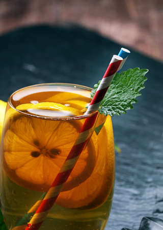 Iced tea with lemon slices, mint and ice on rustic backgroundの写真素材