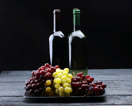Bottle of white wine, grape and corks on wooden tableの写真素材