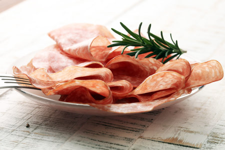 thinly sliced salami on a wooden texture on the backgroundの写真素材