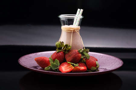 Strawberry smoothie or milkshake in jar on black rustic background, healthy food for breakfast and snackの写真素材