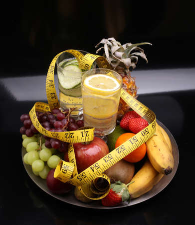 fitness equipment and healthy food and detox water (green apple, pepper, grapes, nectarines, kiwi, orange, dumbbells and measuring tape)の写真素材