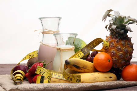 fitness equipment and healthy food - Strawberry Banana smoothie or milkshake(green apple, pepper, grapes, nectarines, kiwi, orange, dumbbells and measuring tape)の写真素材