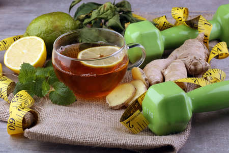 Fitness salad and measuring tape on rustic wooden table. Mixed greens, tomatos, diet cheese, olive oil and spices for healthy lifestyle concept.の写真素材