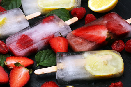 Healthy raspberry, lemon, lime, strawberry popsicles with fresh slices on wooden background