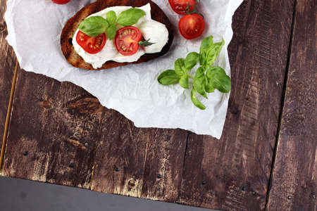 Bread with cream cheese and tomato for lunch table. Sharing antipasti on party or summer picnic time over wooden rustic background.の写真素材