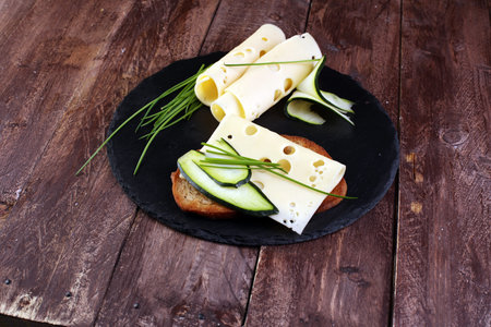 Bread with slices of cheese for lunch table. Sharing antipasti on party or summer picnic time over wooden rustic background.の写真素材