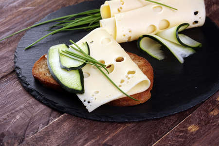Bread with slices of cheese for lunch table. Sharing antipasti on party or summer picnic time over wooden rustic background.の写真素材