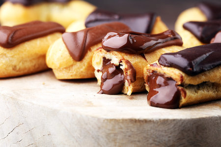 Traditional French dessert. Eclair with chocolate icing. Wooden background
