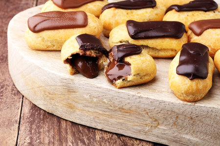 Traditional French dessert. Eclair with chocolate icing. Wooden background