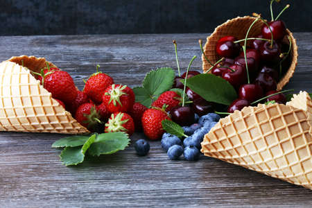 Berries in waffle cones - strawberry, blueberry and black cherry on grey backgroundの写真素材