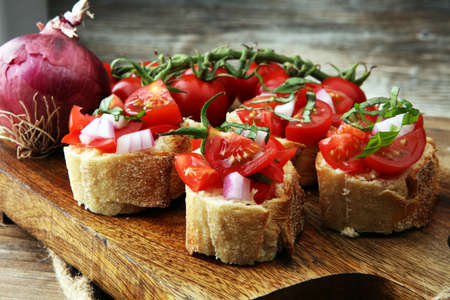 toasted bread with chopped tomatoes on wooden cutting boardの写真素材