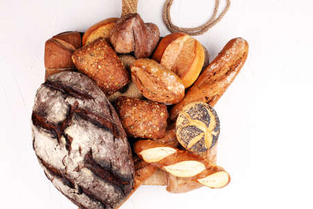 Different kinds of bread rolls on black board from aboveの写真素材