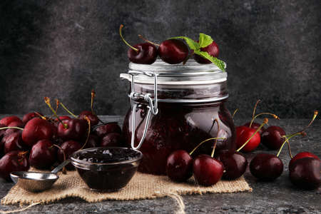 Jar of cherry jam, sour cherries and spoonの写真素材