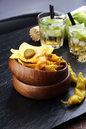 A plate of delicious tortilla nachos with melted cheese sauce, jalapeno peppersの写真素材
