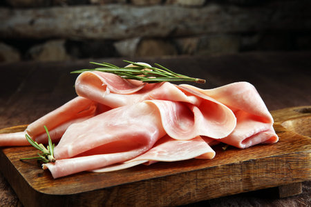 Sliced ham on wooden background. Fresh prosciutto. Pork ham sliced.の写真素材