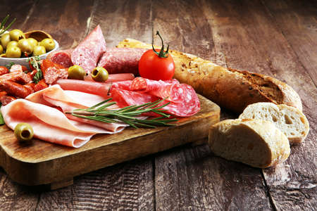 Marble cutting board with prosciutto, bacon, salami and sausages on wooden background. Meat platterの写真素材