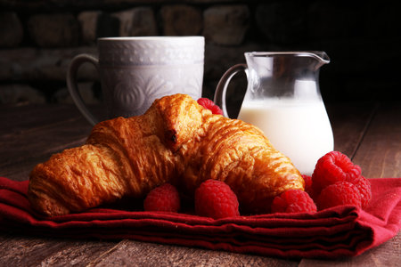 Coffee white cup, croissants on brown wooden background. Breakfast conceptの写真素材