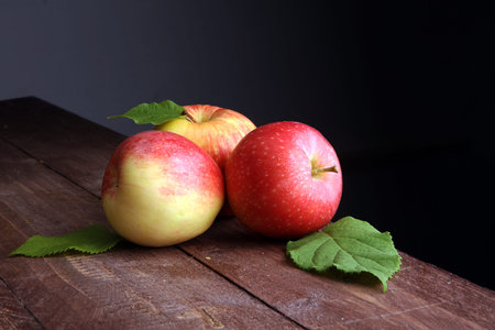 Ripe red apples with leaves on wooden backgroundの写真素材