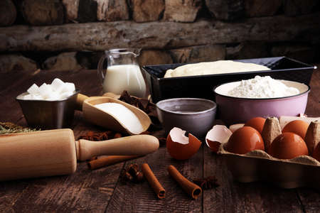 Bakery ingredients - flour, eggs, butter, sugar, yolk, almond nuts on blue table. Sweet pastry baking concept.の写真素材