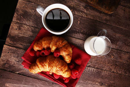 Coffee white cup, croissants on brown wooden background. Breakfast conceptの写真素材