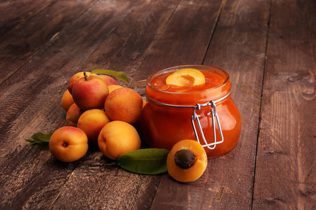 Jam from apricots in a glass jar on a wooden surfaceの写真素材