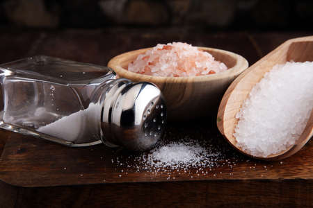 Salt Shaker and salt on wooden table.の写真素材