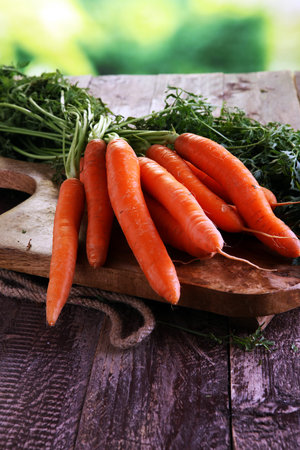 Fresh organic carrots with green leaves on wooden background. Vegetables. Healthy food conceptの写真素材