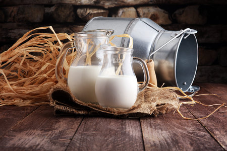 A jug of milk and glass of milk on a wooden table