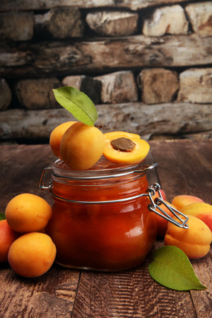 Jam from apricots in a glass jar on a wooden surfaceの写真素材