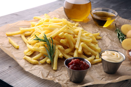french fries, chips on wooden background with salt