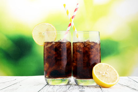 Softdrink with ice cubes, lemon and straw in glass.の写真素材