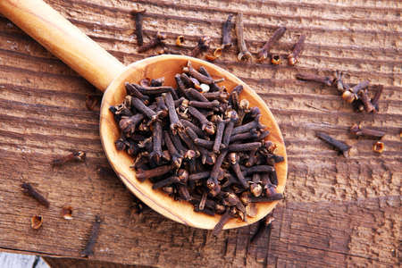 Many Dry cloves spice on brown wooden spoon.の写真素材