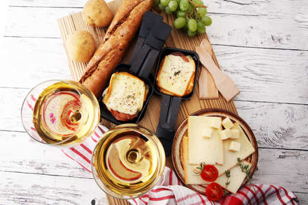 Delicious traditional Swiss melted raclette cheese on diced boiled or baked potato served in individual skillets.の写真素材