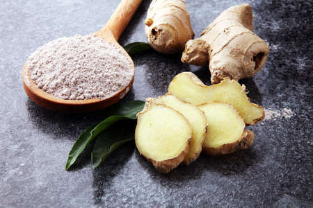 Fresh ginger root and ground ginger spice on dark background.の写真素材