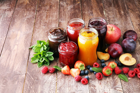 assortment of jams, seasonal berries, plums, mint and fruits の写真素材
