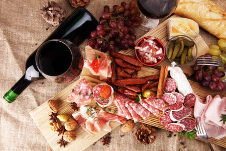 Food tray with delicious salami, pieces of sliced ham, sausage, tomatoes, salad and vegetable - Meat platter with selection - Cutting sausage and cured meatの写真素材