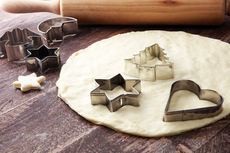 Christmas baking ingredients and tolls for dough preparation. Flour, rolling pin and cookie cutters.