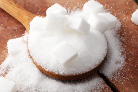 Cubes of sugar and granulated sugar with wooden spoon.