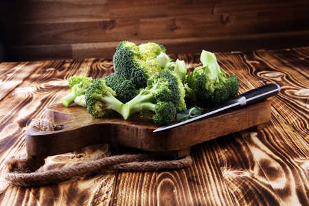 Fresh organic broccoli cut into small pieces on cutting boardの写真素材