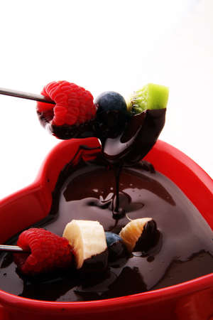 chocolate fondue with fruits assortment on wooden cutting boardの写真素材