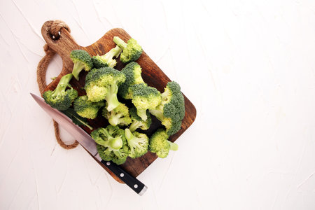 Fresh organic broccoli cut into small pieces on cutting boardの写真素材