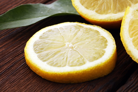 Pile of lemons with leaves on brown wooden table