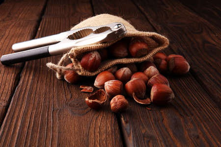 Hazelnut with peeled hazelnuts in burlap on textured wooden backgroundの写真素材