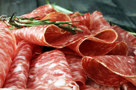 Stone cutting board with sliced salami on it