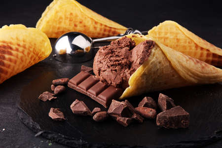 chocolate ice cream scoops with pieces of chocolate and waffle conesの写真素材