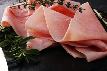 Sliced ham on stone background. Fresh prosciutto. Pork ham sliced.の写真素材