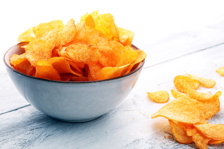 Crispy potato chips. Paprika chips on white wooden background