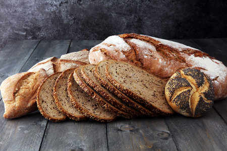 Different kinds of bread and bread rolls on wooden table. Kitchen or bakery poster design
