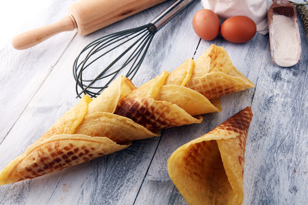 tasty homemade waffle cones on white wooden background